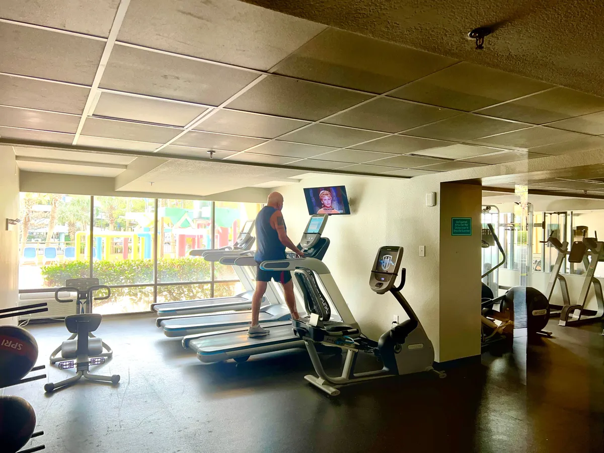 A bright, modern fitness center equipped with treadmills and various exercise equipment, large windows providing a view, and a motivating, active atmosphere. Guests can work out while enjoying natural light and views.