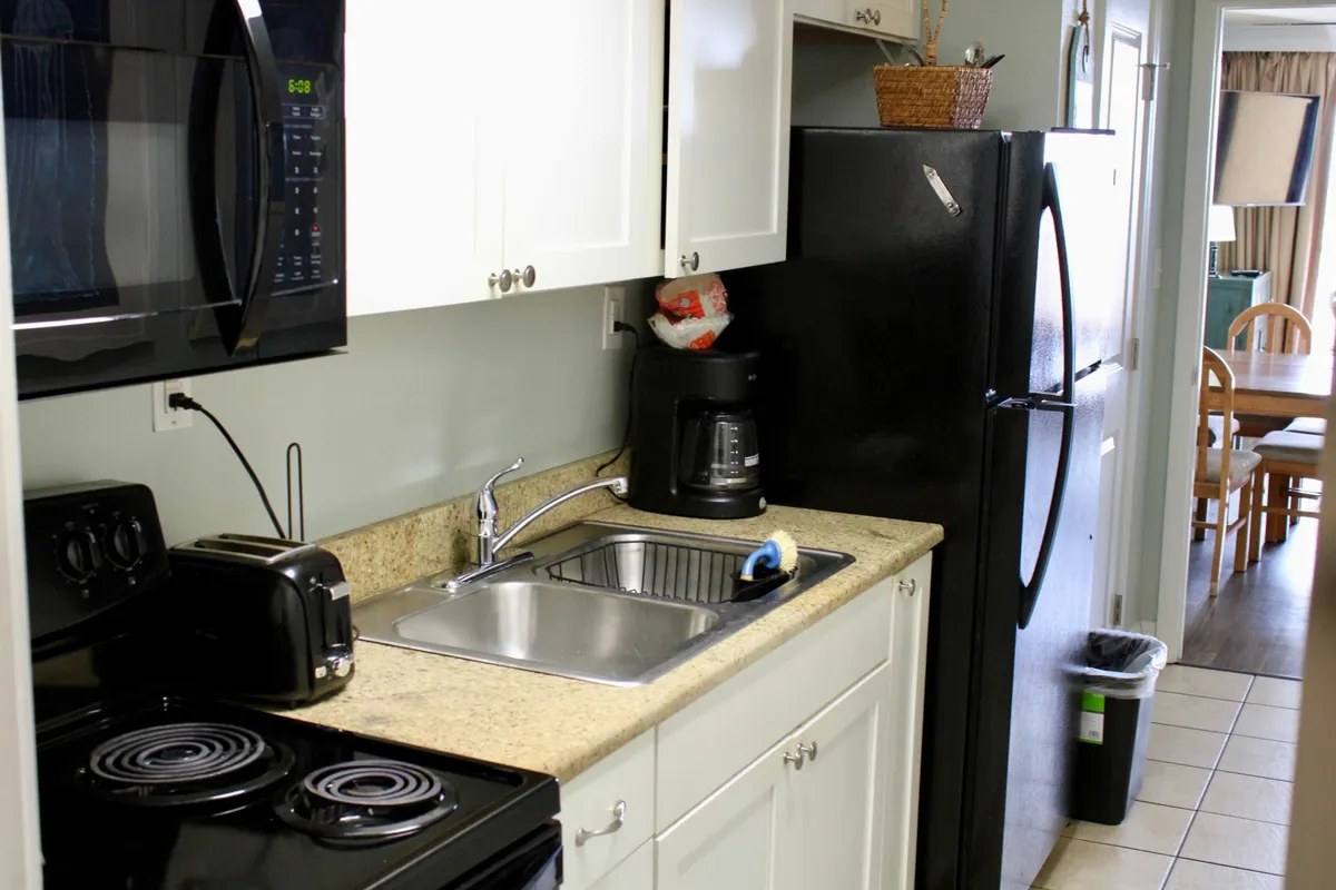 This image showcases a cozy, modern kitchen featuring black appliances, a granite countertop, a kitchen sink, toaster, and coffee maker. The arrangement highlights generous counter space and a variety of essential appliances, with an inviting atmosphere that encourages cooking and socializing.